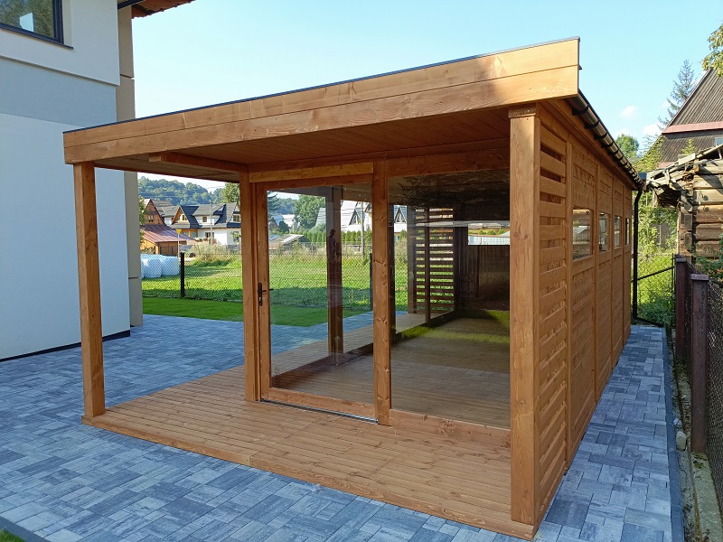 Antracytowa altana szklana z dużymi przeszkleniami i tarasem w nowoczesnym ogrodzie