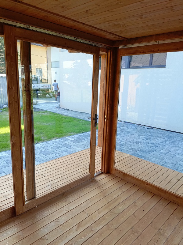 Przestronne wnętrze nowoczesnej altany sosnowej z widokiem na ogród przez duże szyby