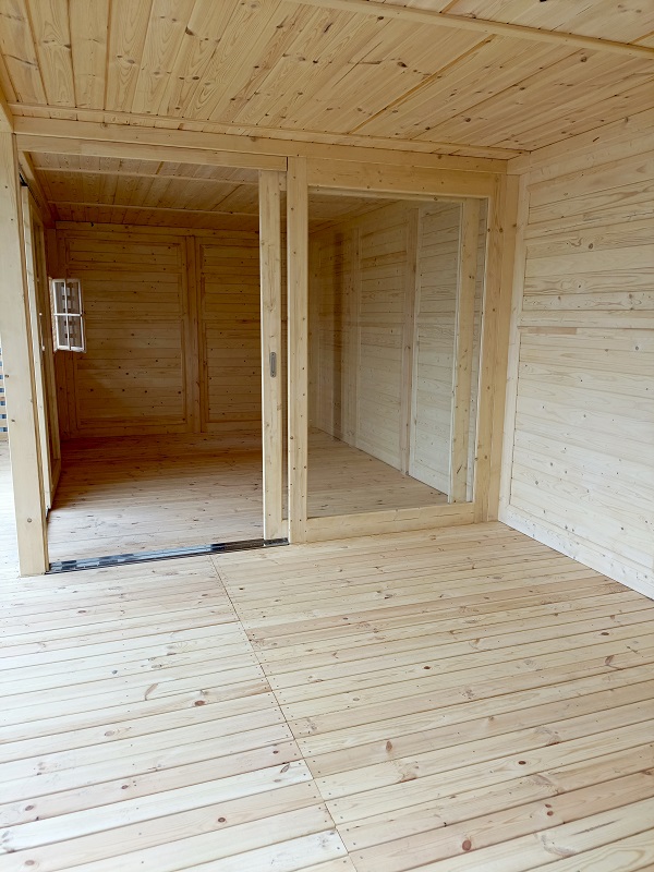 Widok z wnętrza altany na ogród przez panoramiczne drzwi przesuwne